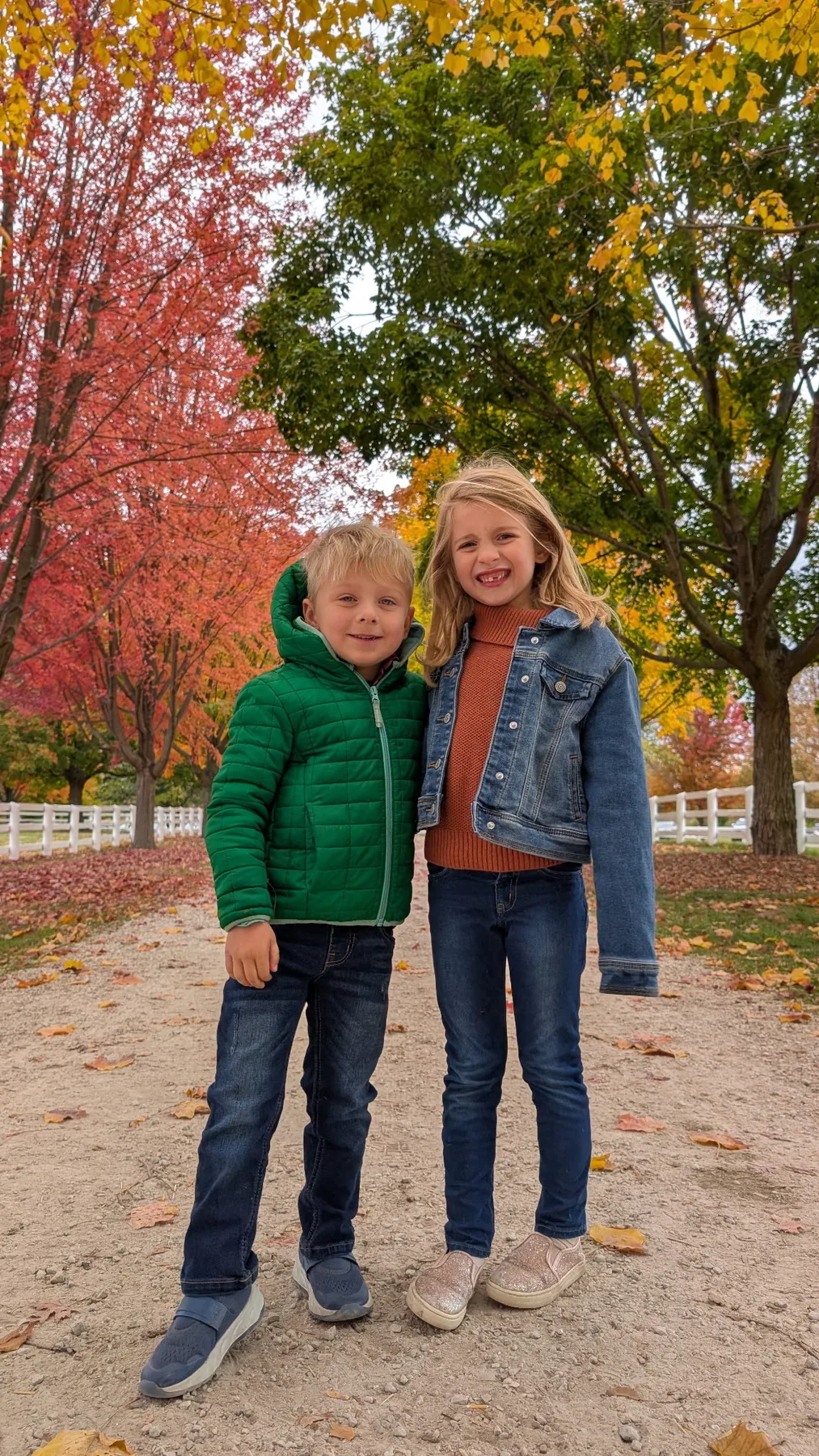 Abigail and Caleb standing under bright autumn trees