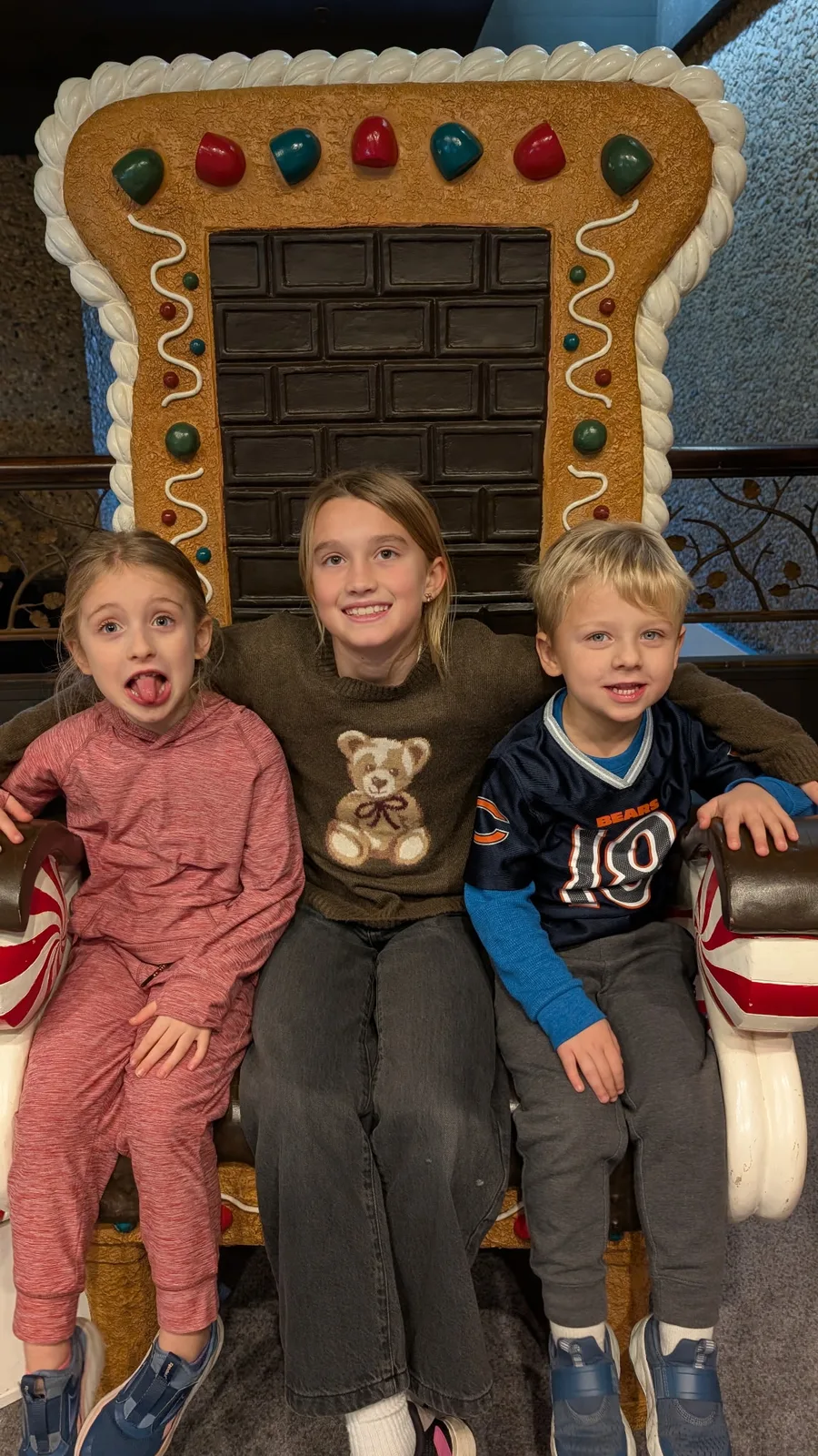 Children posing in front of a giant gingerbread house display